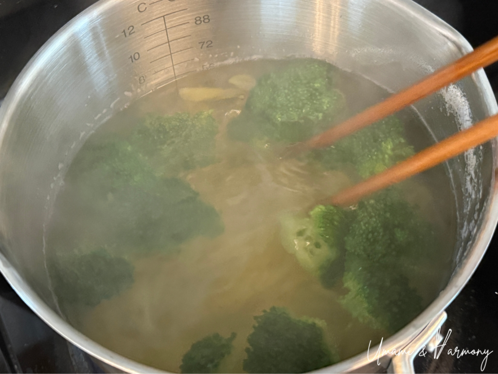 Penne pasta and broccoli boiling together in a pot