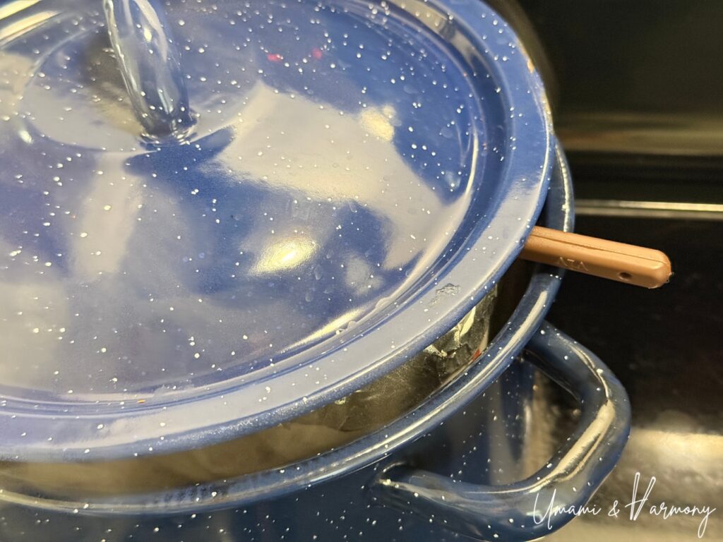 Steamer lid slightly propped open with a chopstick to control heat