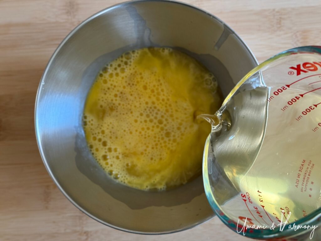 Dashi broth being added to beaten eggs