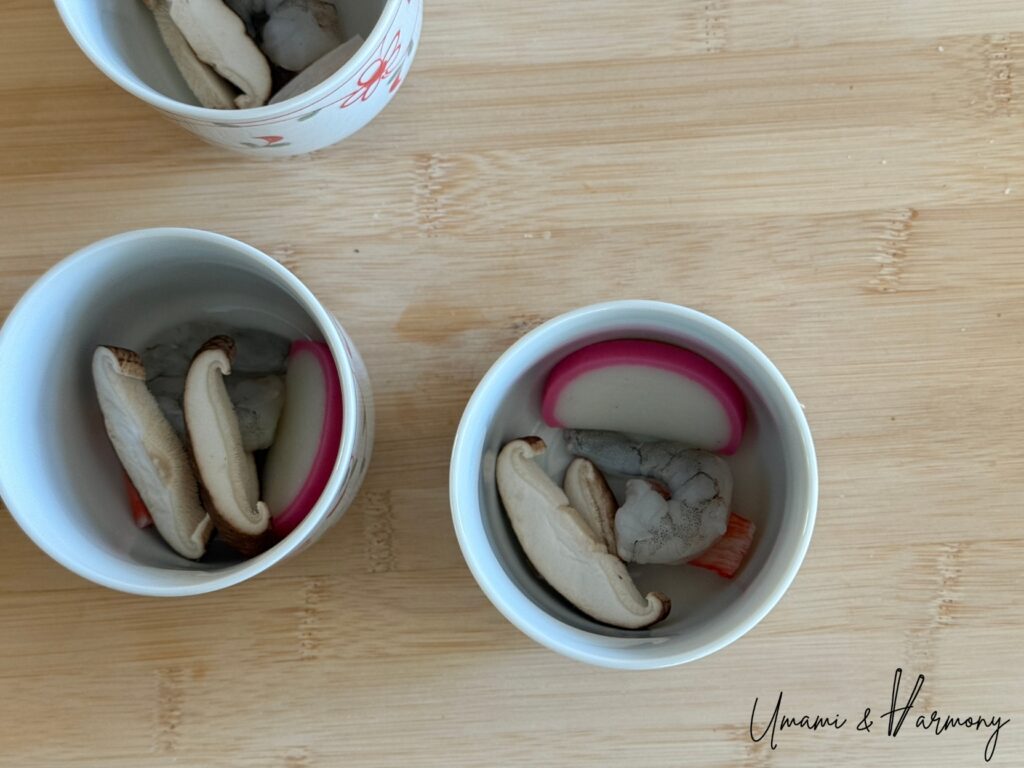 Shrimp, imitation crab sticks, kamaboko, and mushrooms placed into chawanmushi cups