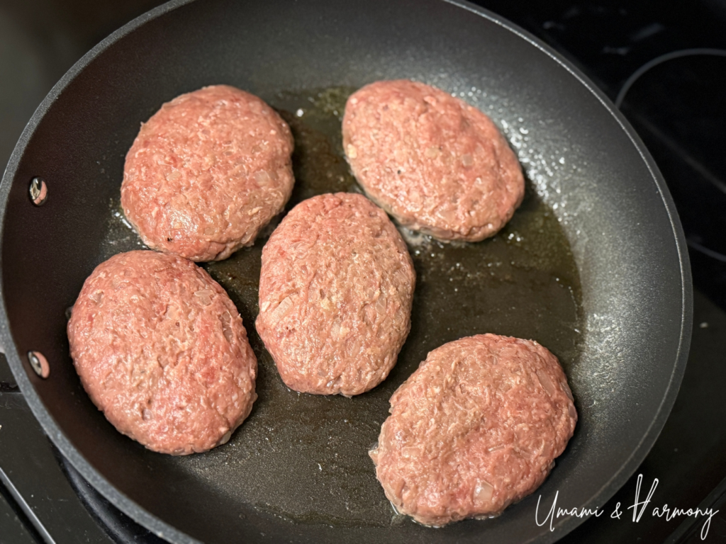 Hamburg steak patties cooking in a frying pan