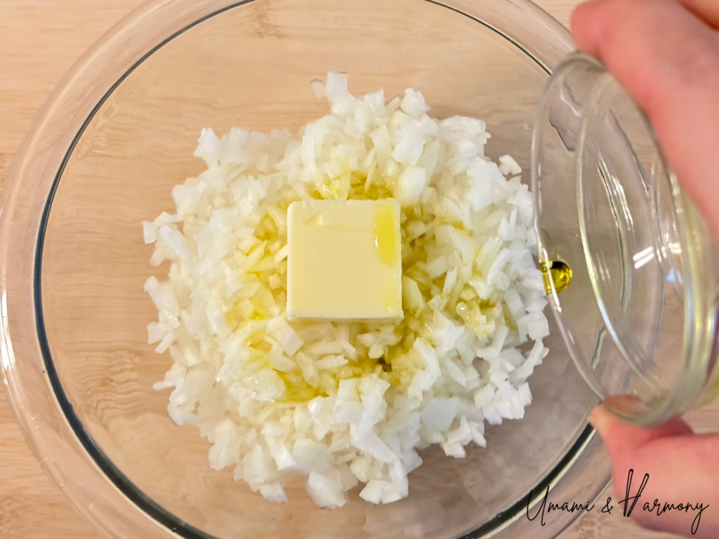 Butter and olive oil added to chopped onion in a glass bowl
