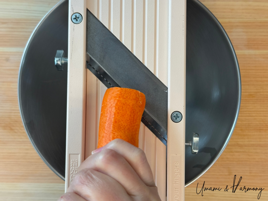 Carrot being sliced into thin strips with a slicer