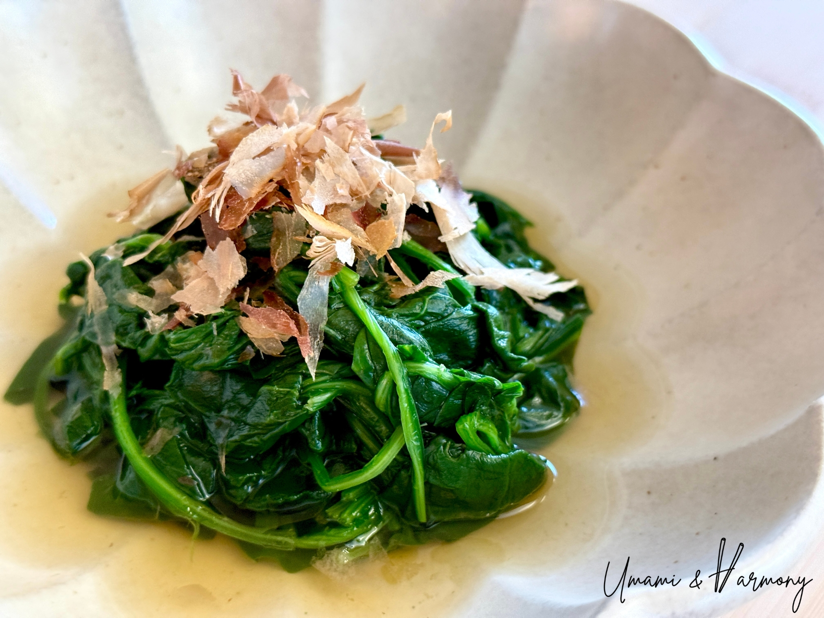 Spinach Ohitashi served in a bowl topped with bonito flakes