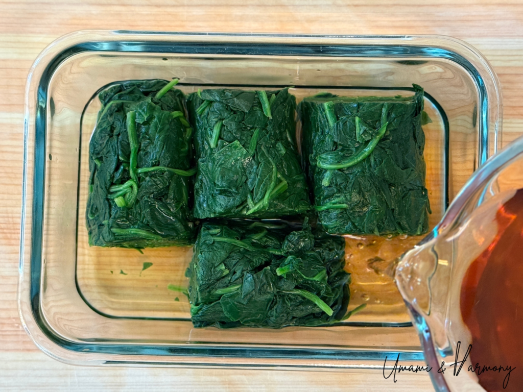 Dashi mixture being poured over the spinach