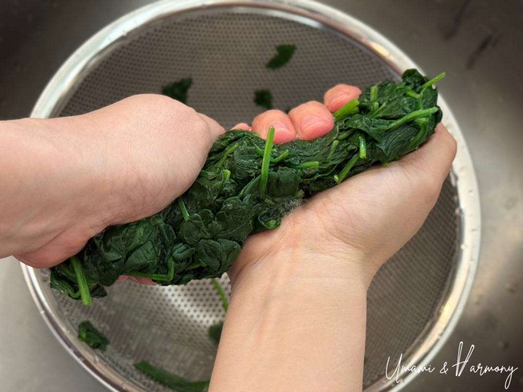Spinach being gently squeezed with hands to remove excess water