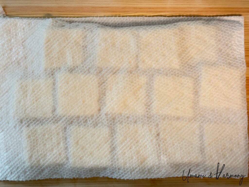 Tofu being drained between paper towels to remove excess moisture