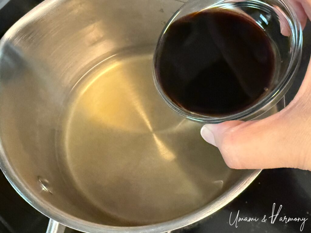 Soy sauce being poured in a pot with dashi 