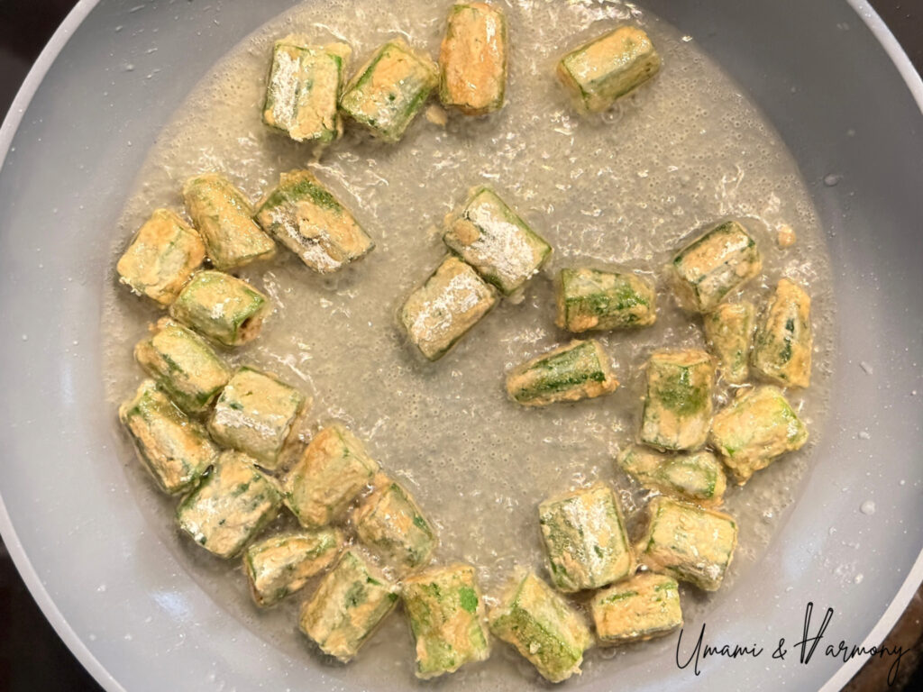 Okra being fried in a pan until lightly golden