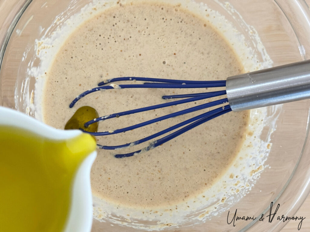 Oil being slowly added to sesame dressing while whisking