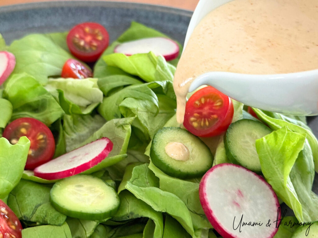 Japanese creamy sesame dressing being poured over fresh salad