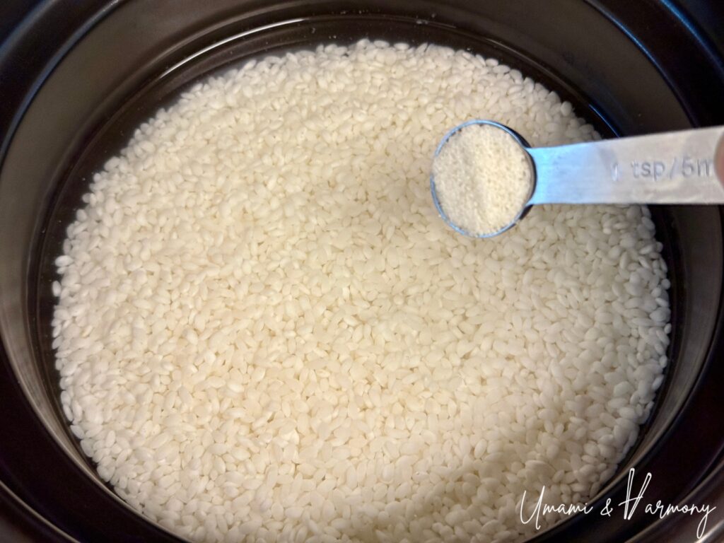 Sea salt being added to the soaked white rice before cooking