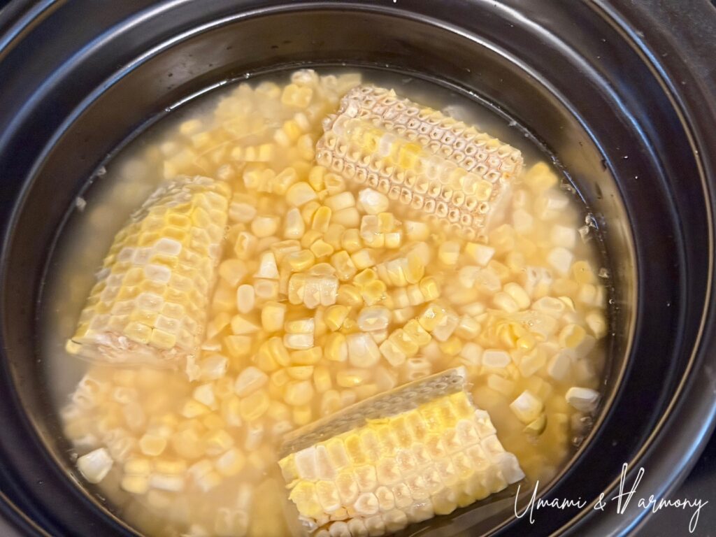 Rice cooker pot with rice, corn, and corn cobs