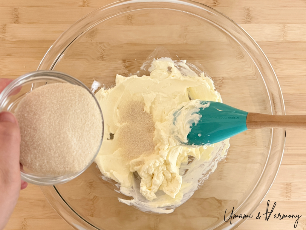 Sugar being added to softened cream cheese