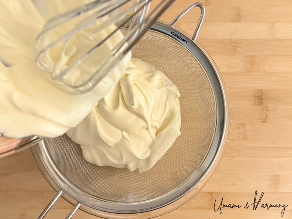 Straining cheesecake filling through a fine mesh sieve
