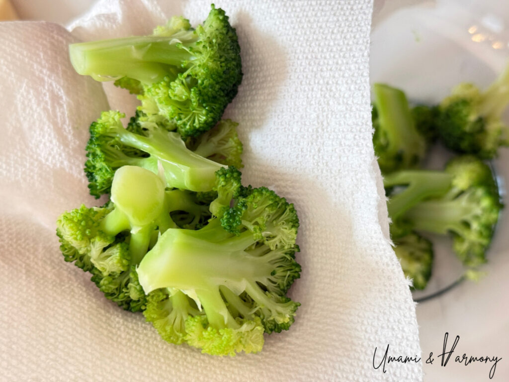 Patting boiled broccoli dry with paper towels