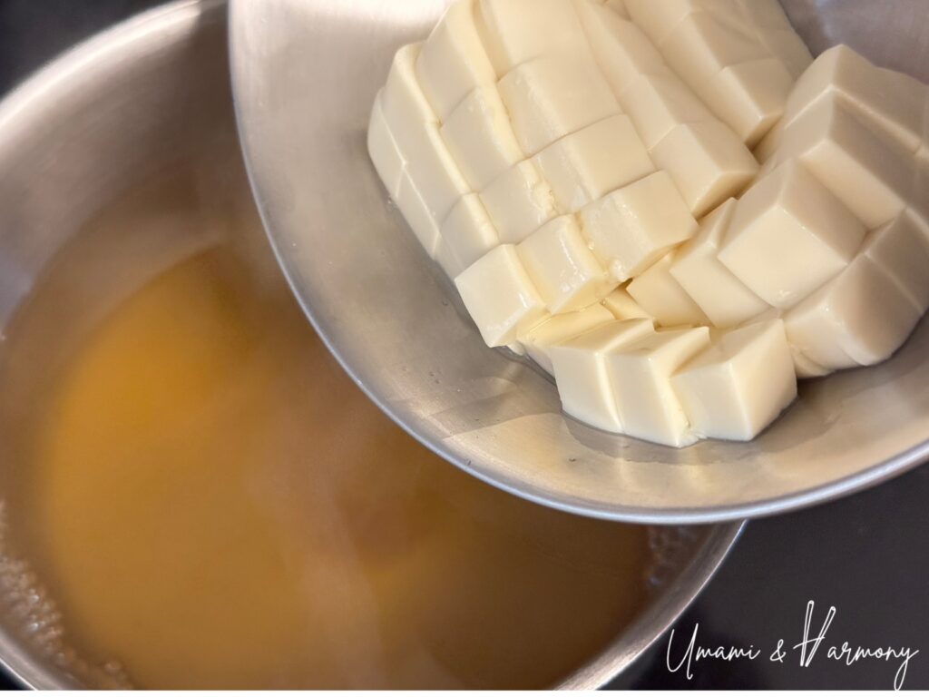 Tofu being added to homemade dashi