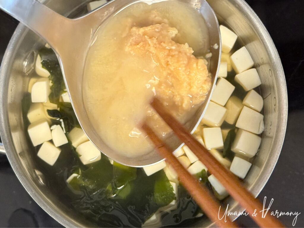 Miso being dissolved in a ladle before adding to soup
