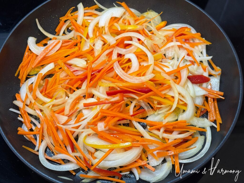 Sliced vegetables being sautéed in a frying pan
